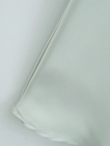Detailed view of mint green silk satin dress fabric showing smooth texture and stitching