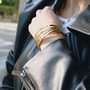 Gros plan d'un bracelet jonc ouvert à quatre couches ondulées en acier plaqué or 18 carats