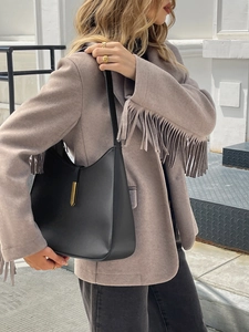 Detailed view of beige fringe blazer paired with black leather crossbody bag and gold accents