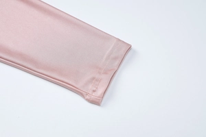 Detailed close-up of pink silk-like fabric texture and fine stitching on the sleeve cuff