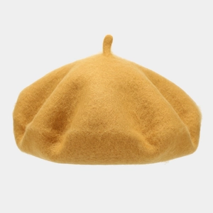 Detail of a mustard yellow wool beret featuring a soft texture and classic top stem detail