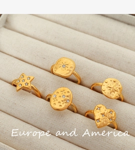 Detail of five gold geometric diamond rings set displayed on a beige velvet jewelry box