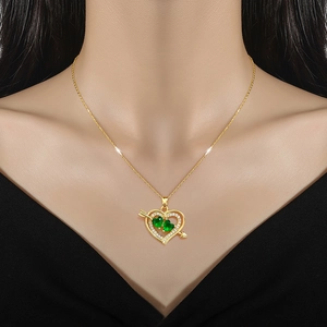 Luxurious gold arrow heart necklace with sparkling diamonds and green gemstones worn on neck