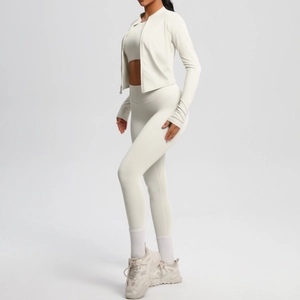 Side view of woman in off-white three-piece yoga set with jacket and high-waisted leggings
