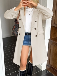 Beige double-breasted long trench coat for women styled with casual denim skirt and boots