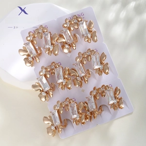 Detailed macro view of six pairs of rose gold earrings with rectangular zircon and butterflies