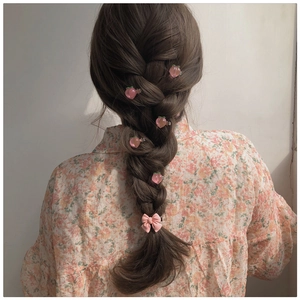 Close-up of pink peach and ribbon hair clips on a girl's braided hair styling