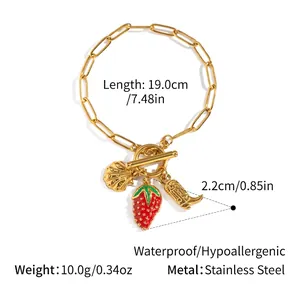 Détail du bracelet en acier inoxydable doré 18 carats avec breloques fraise, coquille et botte