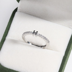 Macro shot of silver letter H ring with crystal inlay in green velvet jewelry box