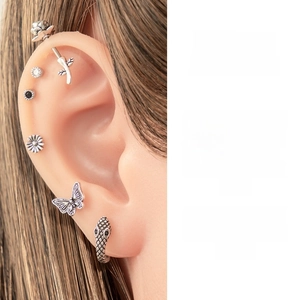 Detailed view of vintage silver butterfly and rose stud earrings on a silicone ear model