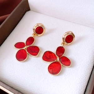 Macro shot of vintage red enamel flower earrings with gold metal frame on a jewelry box