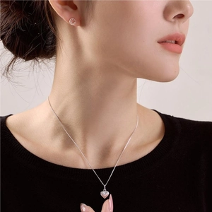 Close-up of 925 sterling silver heart necklace and simple round stud earrings on a model