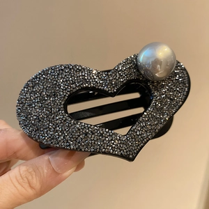 Detail of heart hair claw clip with black rhinestones and a large silver faux pearl