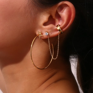Detail of gold star hoop earring and chain cartilage cuff set on model ear