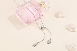 Détail du collier argenté avec pendentifs garçon et fille et fermoir en forme de cœur