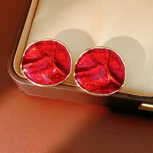 Modern red enamel round stud earrings with gold trim and artistic lava texture