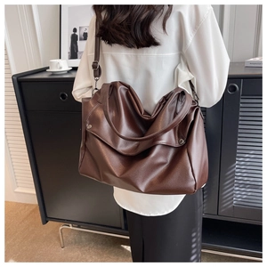 Rear view of a model wearing the large brown lychee leather tote bag with long shoulder straps