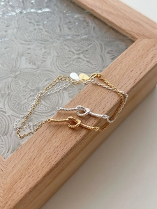 Detail of gold and silver S925 sterling silver woven knot bracelets on a wooden frame