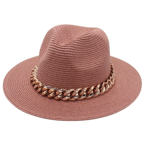 Chapeau Fedora en paille rouge brique avec une grosse chaîne dorée pour un look plage