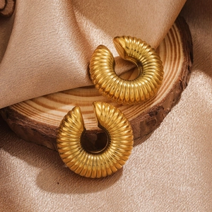 Vintage gold twisted C-shape earrings with textured stripes on a wooden base