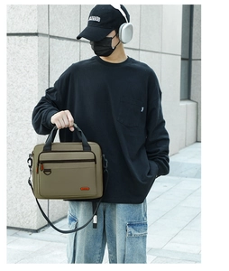 Detailed view of khaki canvas briefcase with reinforced handle and orange fashion label
