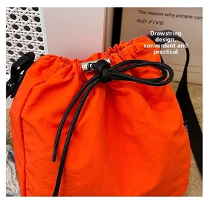 Detail of bright orange nylon drawstring bucket bag showing drawstring closure and metal lock