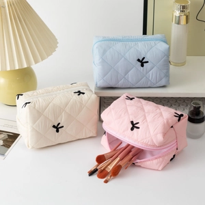 Quilted cotton cosmetic bags in blue, white, and pink with ribbon bows and makeup brushes
