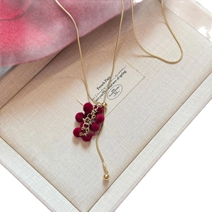 Elegant gold chain necklace featuring red flocked grape cluster pendant in a jewelry box