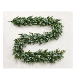 Detail of lush green artificial pine garland with realistic brown pinecones on light base