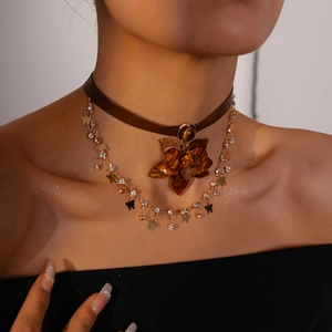 Detail of vintage flower pendant with butterfly tassels on brown leather choker necklace