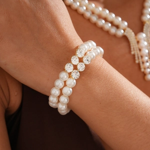 Close-up of double-strand pearl bracelet with golden crystal bar on woman's wrist