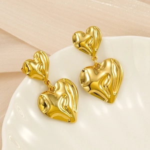 Detail of 18K gold-plated hammered heart earrings on elegant white ceramic tray