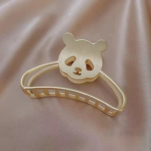 Detail of a 8cm gold panda hair claw clip with brushed metal texture on silk background