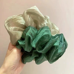 Detail of silk organza hair scrunchies in peacock green and white with shimmer texture