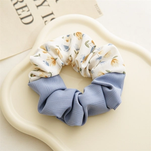 Detailed view of floral print fabric scrunchie with blue twill texture on a decorative tray