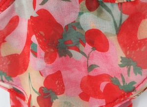 Dettaglio del tessuto in chiffon rosa e giallo con stampe di fragole rosse e foglie