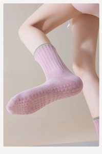 Pink yoga socks with green trim and anti-slip silicone grip dots on the sole