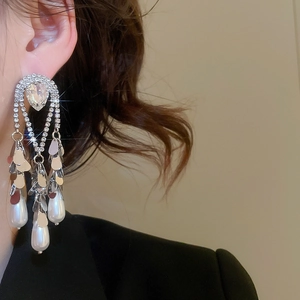 Detailed view of long tassel earrings with teardrop pearls and rhinestones on a model