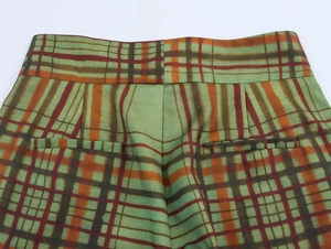 Dettaglio dei pantaloni a quadri a vita alta in verde e arancione con tasche posteriori