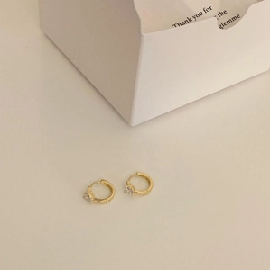 Detail of small gold hoop earrings with clear cubic zirconia in a minimalist style