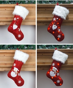 Detail of red Christmas stockings with LED lights and white faux fur trim on a fireplace