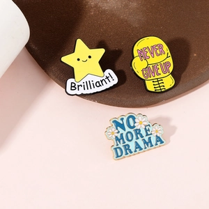 Flat lay of star and boxing glove enamel pins on a brown tray over a pink backdrop