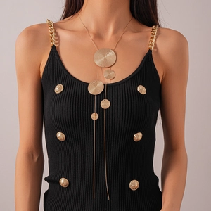 Detail view of a long gold tassel necklace with textured circular metal discs on a model