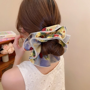 Detailed view of an oversized floral print scrunchie used for an elegant hair bun style