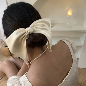 Elegant oversized cream satin bow hair clip with pearl charms worn on a low bun