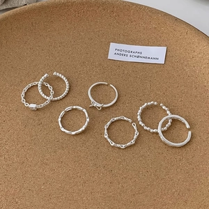Detailed set of 8 silver twist and chain open rings displayed on a cork tray
