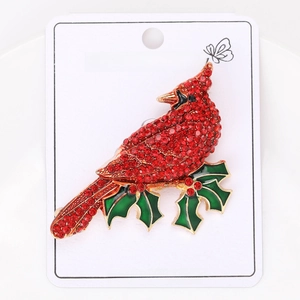 Detailed view of red cardinal brooch with sparkling rhinestones and green holly leaves