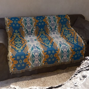 Detail of bohemian geometric woven blanket with tassels on a dark brown leather sofa