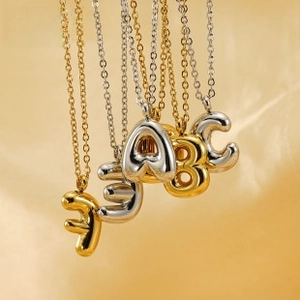 Macro view of gold and silver balloon-style alphabet pendants on fine link chains