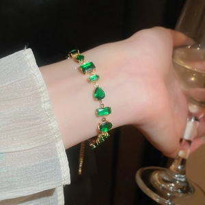 Detail view of emerald green multi-shape cubic zirconia bracelet with golden base